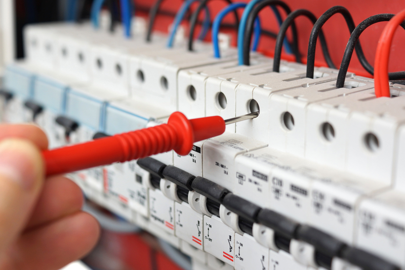Hand of an electrician with multimeter probe at an electrical sw multimeter probe